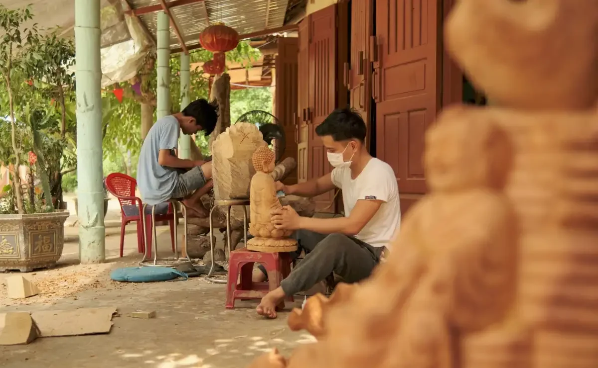 Artisan hand-carving a wooden zodiac souvenir in Kim Bong village