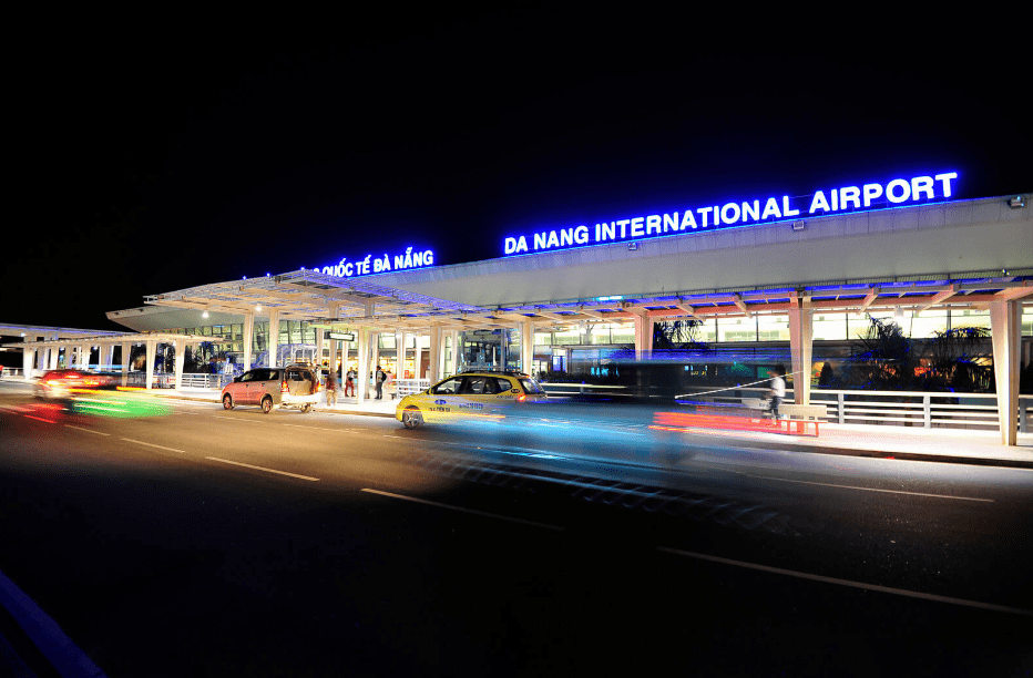 How to get from Da Nang Airport to Hoi An - Airport arrivals exit at night, terminal signage lit up, a short line of taxis visible outside (Source: Collected)