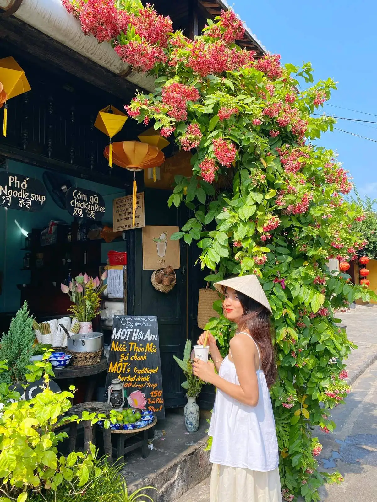 Un touriste goûtant la boisson Mot à Hoi An tout en flânant dans la vieille ville illuminée par les lanternes