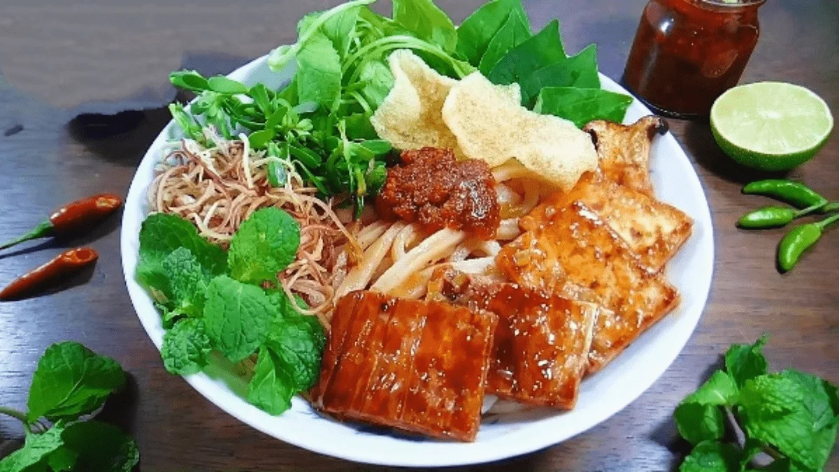 Flat lay of Vietnamese dong notes next to a plate of cao lau noodles (Source: Collected)