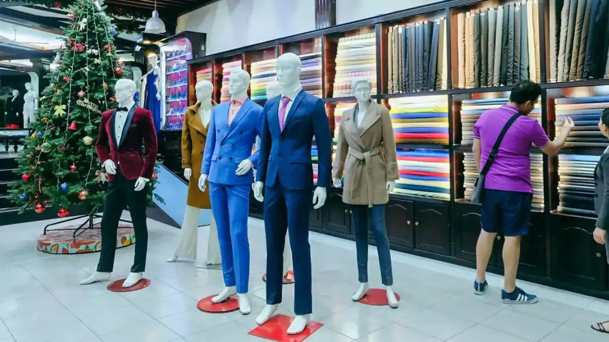 The interior of a large tailor shop in Hoi An, featuring shelves stacked with colorful bolts of fabric (Source: Vietnam)