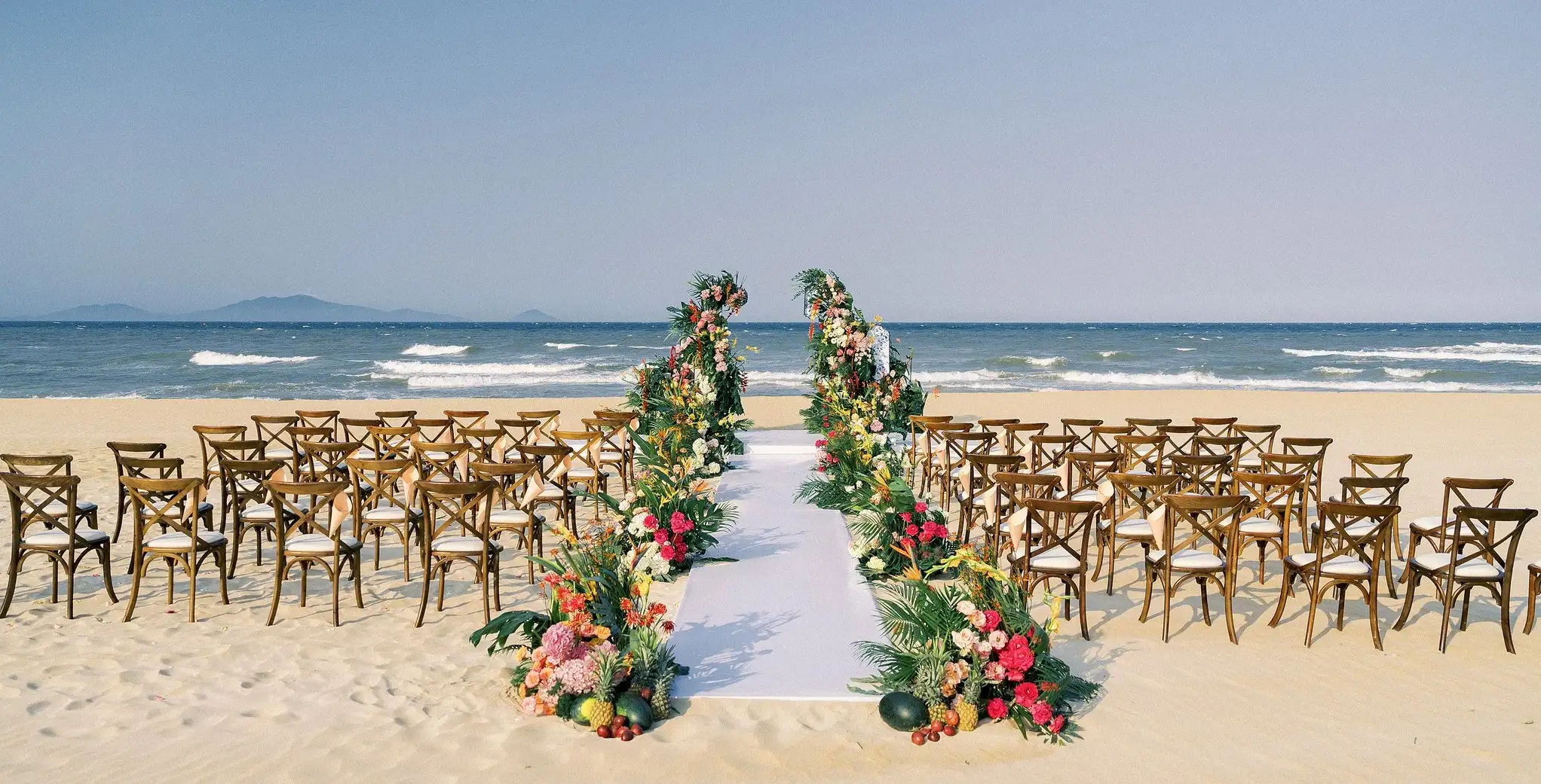 A line-item wedding budget spreadsheet next to a laptop, with a calculator and sample seafood banquet dish nearby