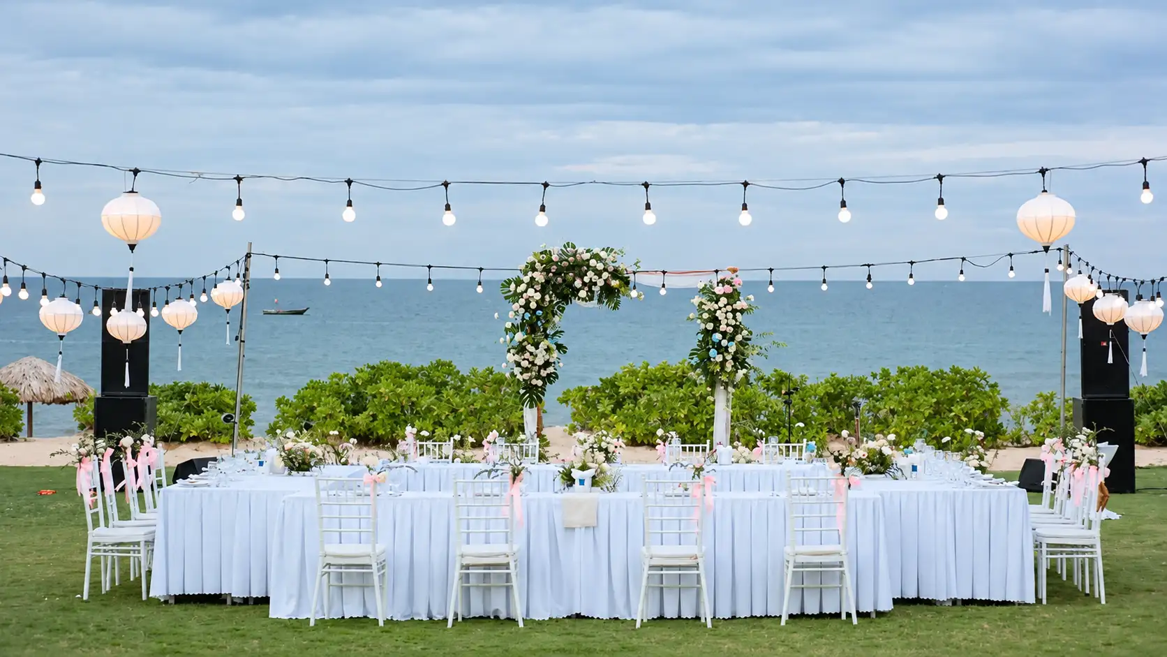 Outdoor wedding reception setup at Bliss Hoi An, dining tables set along Binh Minh Beach at sunset