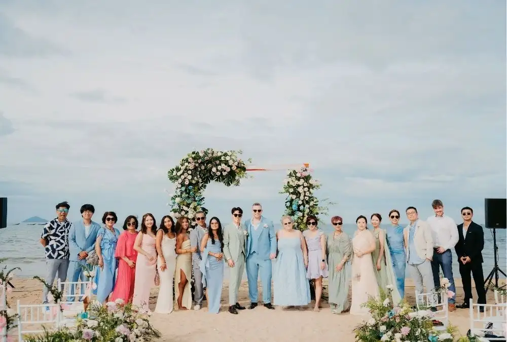Family and friends gather for a group photo in front of the floral arch on Binh Minh Beach