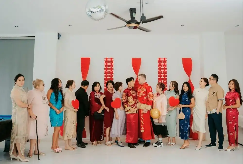 Daniel and Kieran in red, surrounded by relatives in colorful cheongsams before the tea ceremony begins