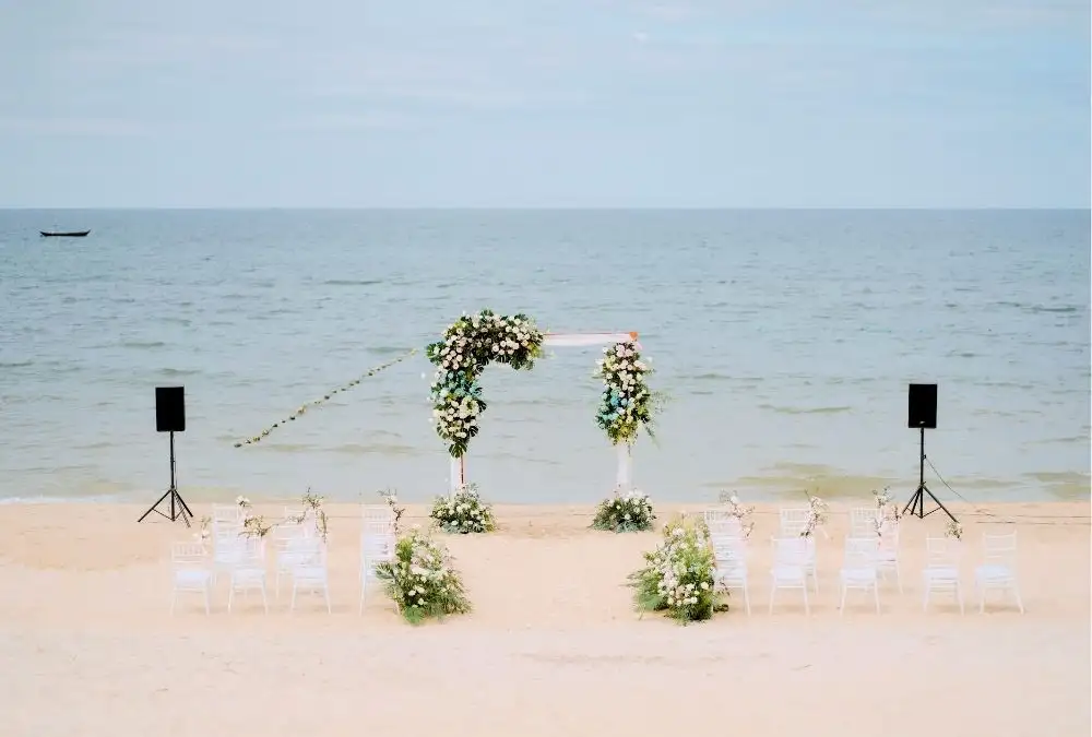 The aisle on Binh Minh Beach before the ceremony: white chairs, a floral arch and the open sea