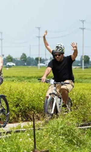 Cyclist on a quiet rice-field road outside Hoi An at sunrise Travelers cycling along the scenic route from Cam An to Hoi An